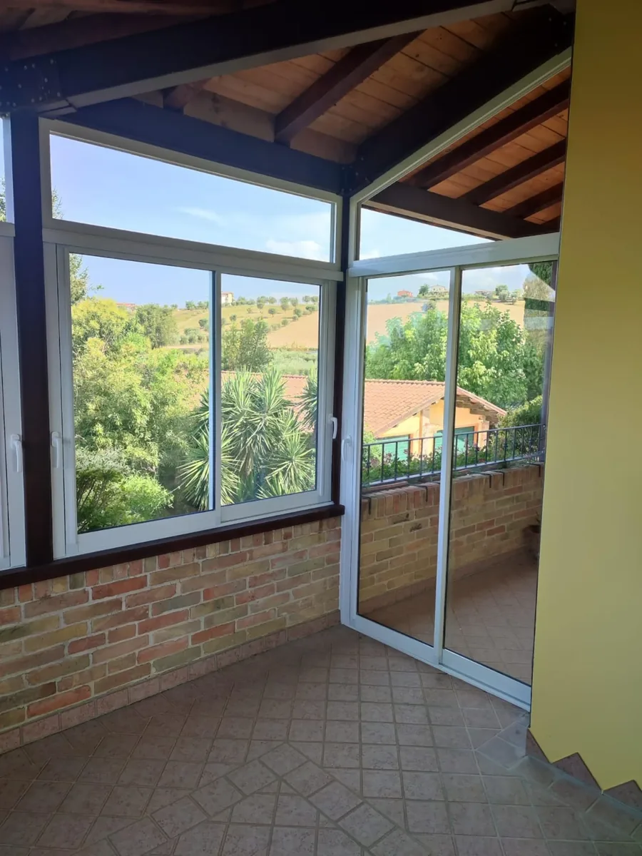Veranda chiusa con finestre scorrevoli in alluminio bianco e vista panoramica sulle colline - IS Metal srl